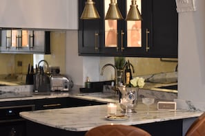 A kitchen with marble countertops, a wine glass, a candle, and a vase with flowers. - Princes Street Townhouse (Bath)