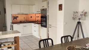 Une cuisine moderne avec des meubles blancs, un plan de travail en marbre et un coin repas comprenant une table et des chaises.