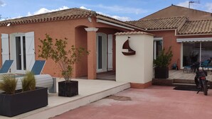 Une maison avec une piscine, un espace salon extérieur et un vélo garé devant.