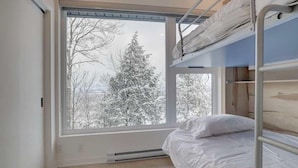 Una habitación con literas, un ventanal grande y vistas a árboles nevados.