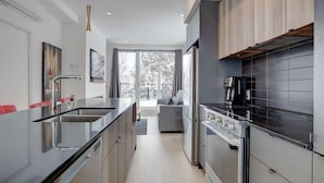 Una cocina moderna con una isla central, electrodomésticos de acero inoxidable y vistas al salón.