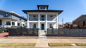A two-story building with a green door, a balcony, and a gated entrance. - Regal Retreat with City Views (Raleigh)