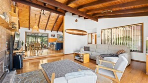 A spacious living area with a wooden ceiling, a sofa, a coffee table, and a fireplace. - 93 Montague Ave Kianga (Kianga)