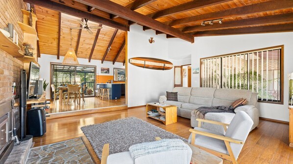 A spacious living area with a wooden ceiling, a sofa, a coffee table, and a fireplace.