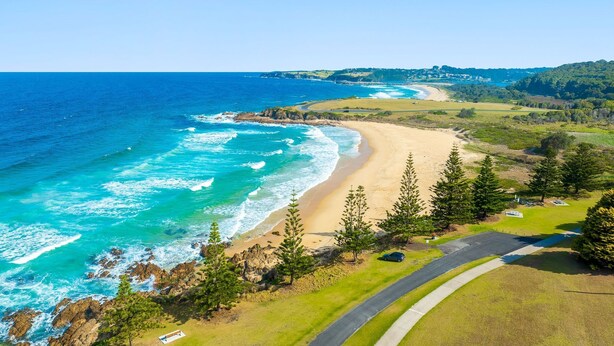 A coastal road with a beach and ocean on one side, and a grassy area with trees on the other. - 93 Montague Ave Kianga (Kianga)