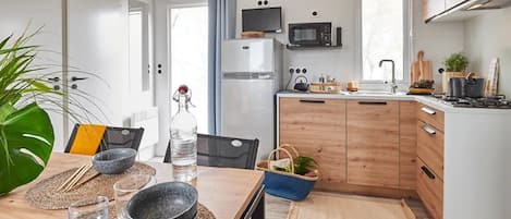 Una cocina moderna con armarios de madera, un refrigerador, un microondas y un lavamanos.