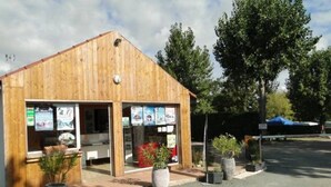 Ein Holzhaus mit geneigtem Dach, großen Fenstern und einem kleinen Eingang. Vor dem Gebäude stehen Blumentöpfe.