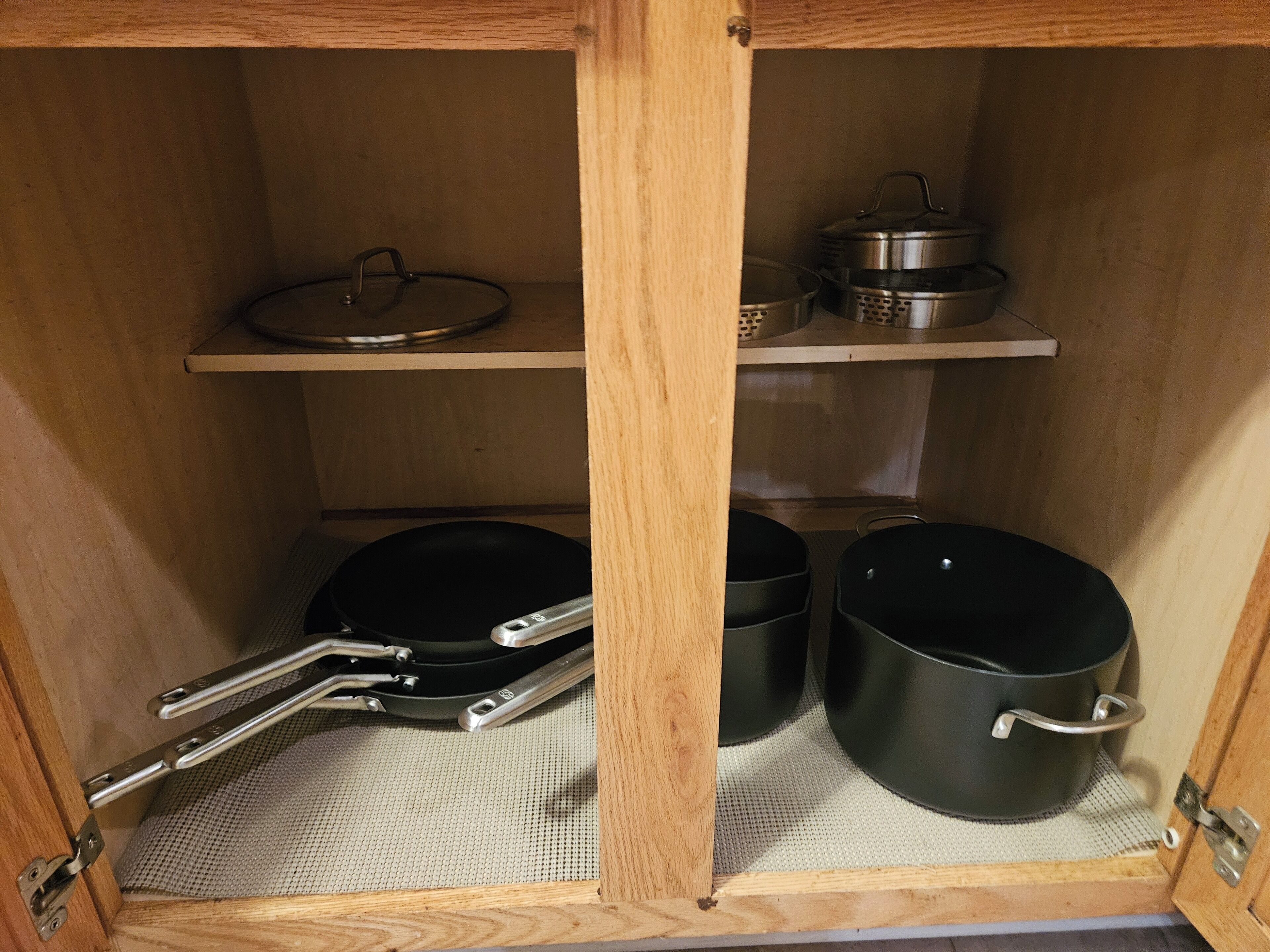 A wooden cabinet with shelves holding cookware, including pots and pans.