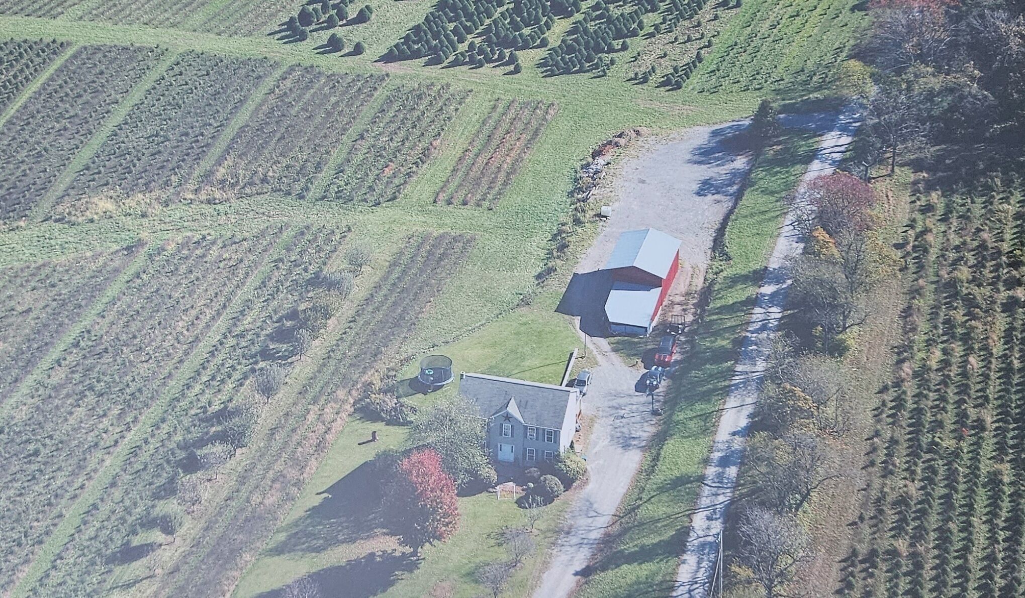 Luchtbeeld van een landgoed met een groot huis, een schuur en omliggende velden.