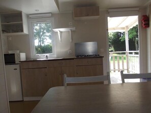 A compact kitchen with a dining area, a built-in microwave, a gas stove, and a window providing natural light.