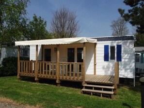 A mobile home with a wooden deck and a covered porch.