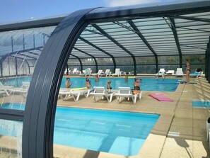 Una piscina coperta con lettini da relax e una struttura in vetro.