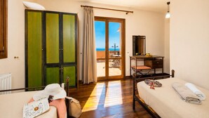 Ein Schlafzimmer mit Bett, Schreibtisch, Stuhl, Kleiderschrank und Meerblick.