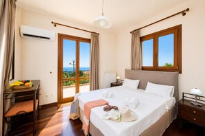 Ein Schlafzimmer mit Bett, Nachttisch, Lampe, Fenster und Blick ins Freie.