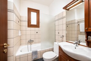 Ein Badezimmer mit Badewanne, Toilette, Waschbecken und Spiegel.