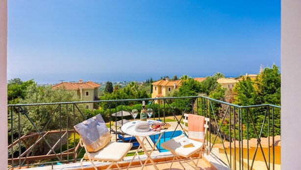 A balcony with outdoor seating, a pool, and a view of the sea and surrounding buildings. - Ionian Blue - Three Bedroom Villa, Sleeps 7 (Svoronata)