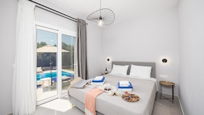 Ein modernes Schlafzimmer mit einem großen Bett, Blick auf einen Swimmingpool und einer Schiebeglastür.