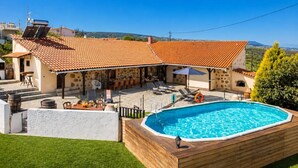 Een villa met zwembad, terras en uitzicht op de heuvels.