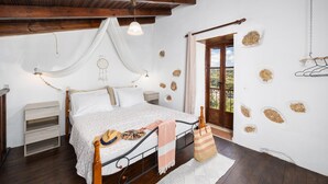 Een slaapkamer met een bed, nachtkastjes, een gitaar en uitzicht op het landschap.