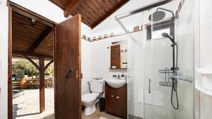 Een badkamer met een douchecabine van glas, een toilet en een wastafel.