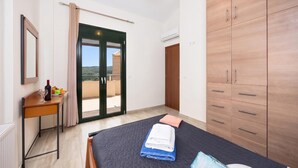 A bedroom with a bed, a desk, a wardrobe, and a sliding glass door to a balcony. - Villa Olive - Four Bedroom Villa, Sleeps 7 (Gerani)