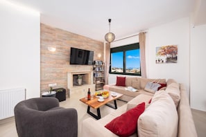 Un salon moderne avec une cheminée, un canapé, une table basse et un téléviseur fixé au mur.