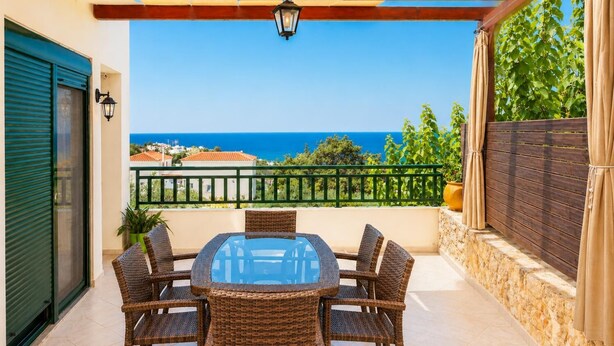 A covered patio with a table and chairs, a view of the sea, and a wooden pergola. - Villa Olive - Four Bedroom Villa, Sleeps 7 (Gerani)