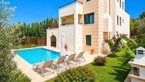 A modern two-story house with a swimming pool, outdoor seating, and a well-maintained garden. - Villa Olive - Four Bedroom Villa, Sleeps 7 (Gerani)
