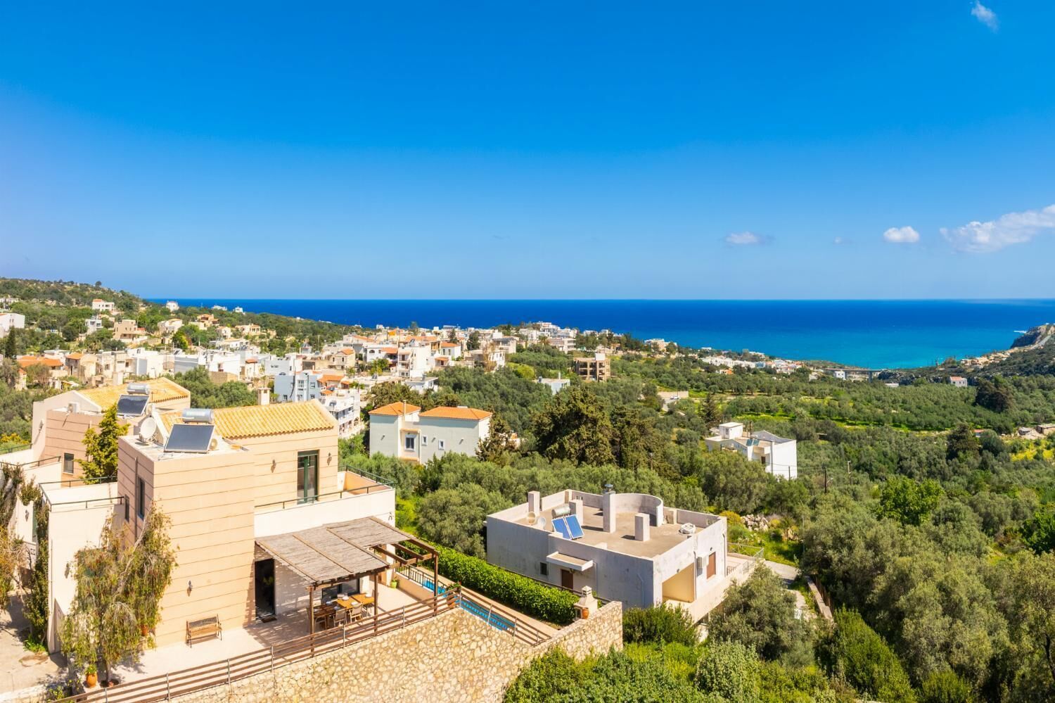 A coastal residential area with houses, a swimming pool, and a view of the sea.