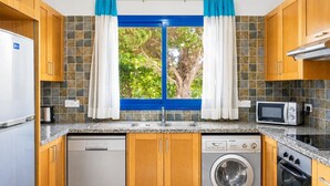 Een keuken met een vaatwasser, wasmachine, magnetron en oven.