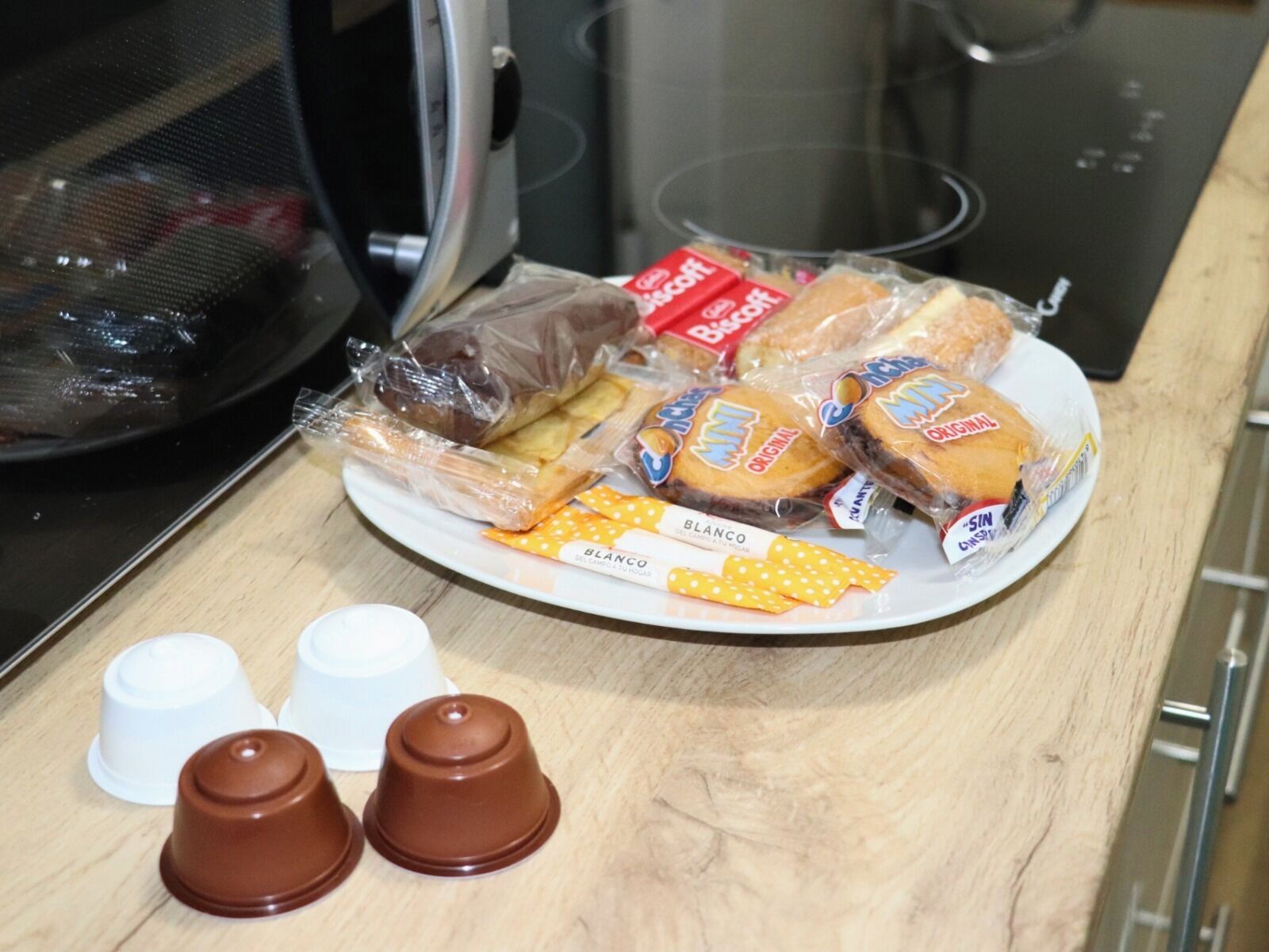 A plate with various packaged food items, including biscuits and crackers, on a wooden surface.
