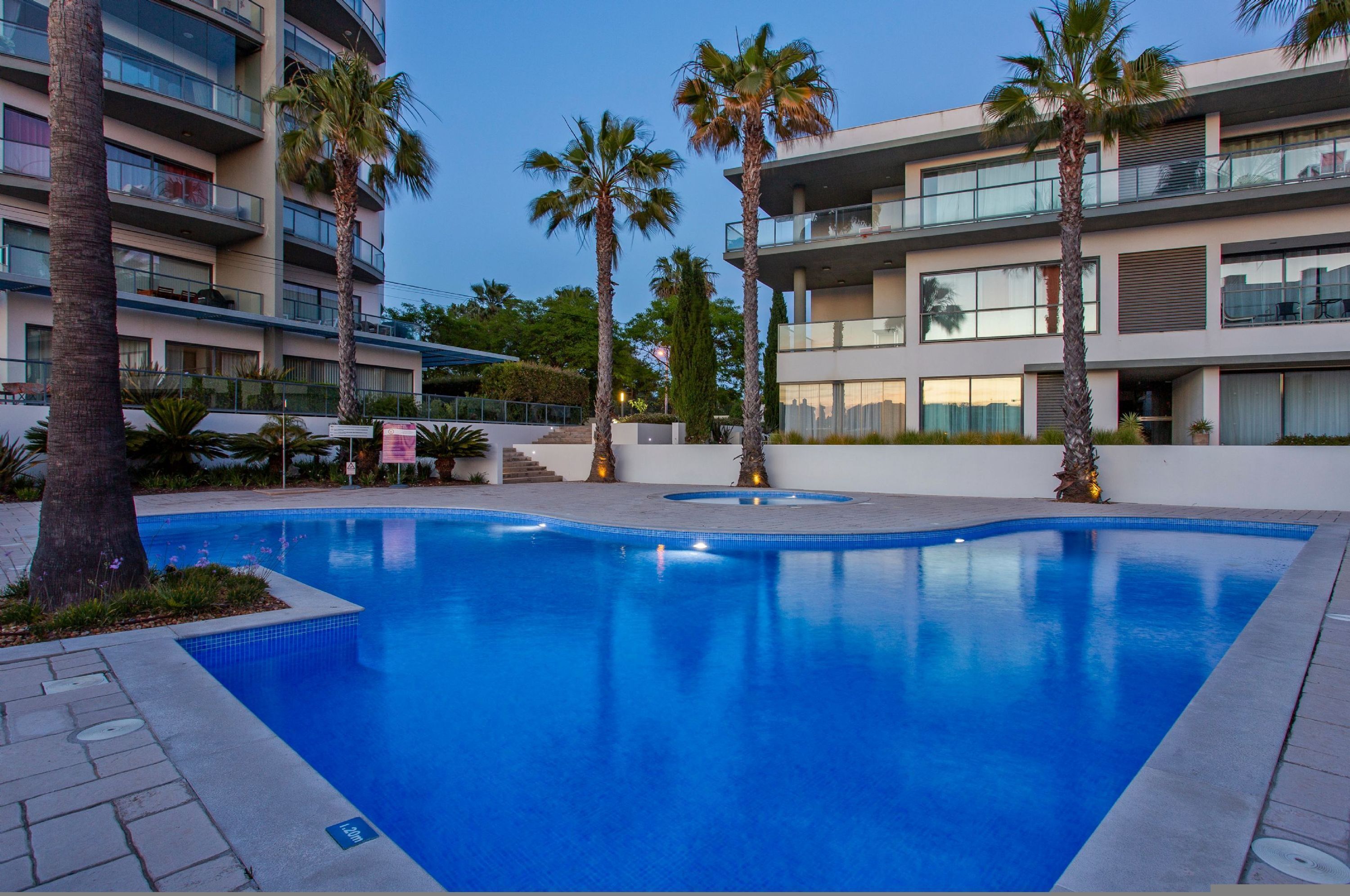 Una piscina circondata da palme e edifici moderni.