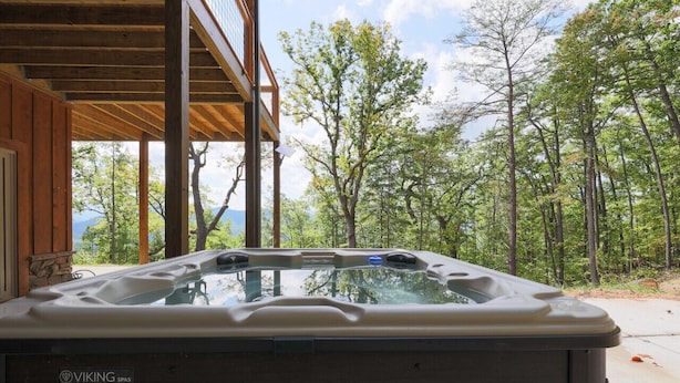 A Viking Spas hot tub in a wooden cabin with a balcony overlooking a forested area. - 3 Bed | 4 Bath Mountain Escape in Wears Valley (Sevierville)