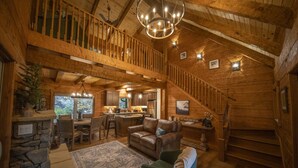 A spacious wooden cabin with a dining area, kitchen, and a staircase leading to a loft. - 3 Bed | 4 Bath Mountain Escape in Wears Valley (Sevierville)