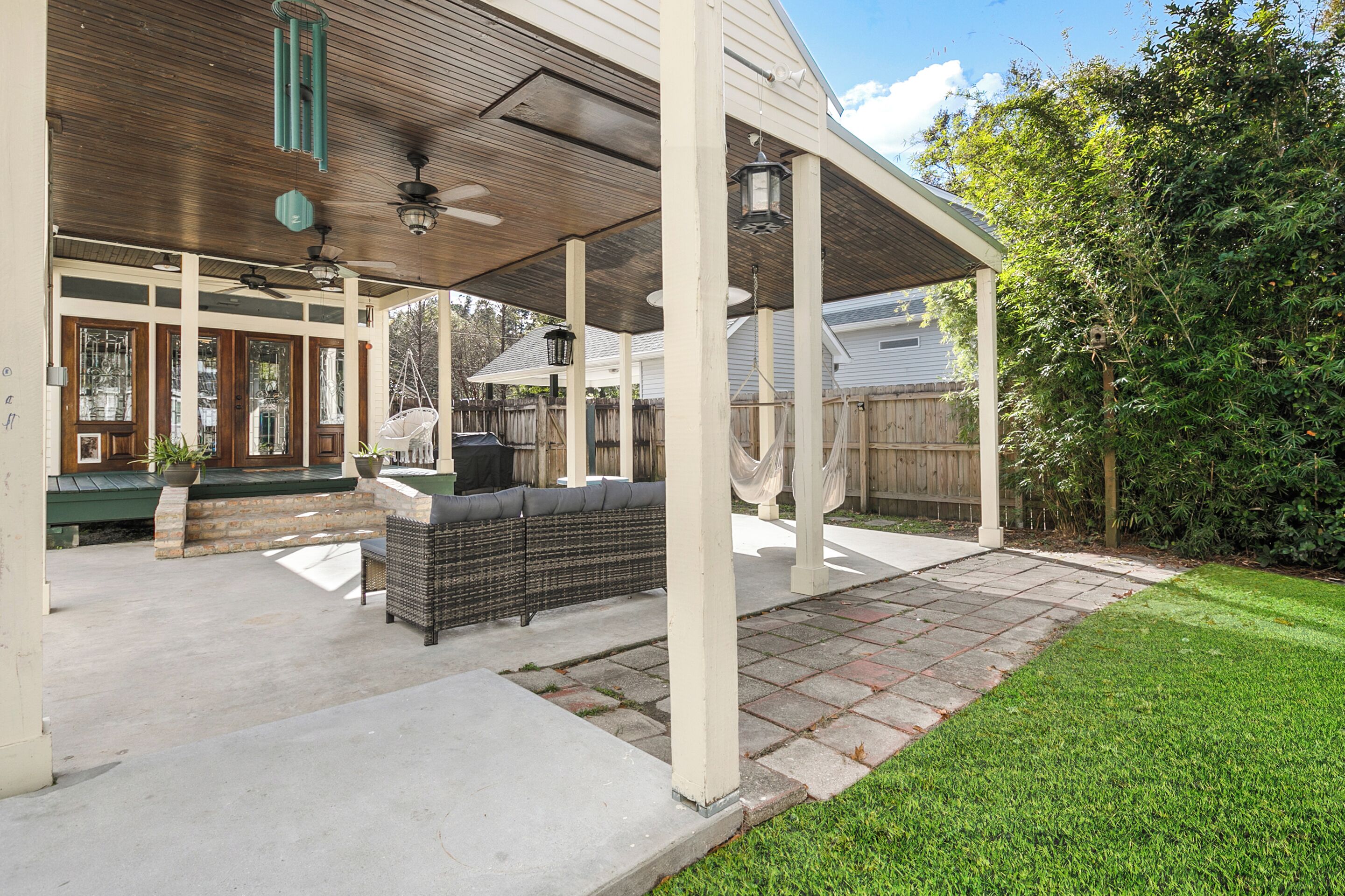 A covered patio area with outdoor seating, a pergola, and a view of a house in the background.