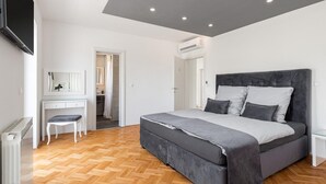 A modern bedroom with a large bed, a desk, and a chair.