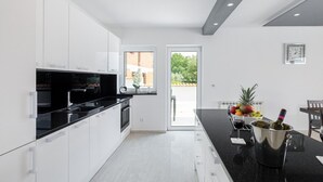 A modern kitchen with white cabinets, a black countertop, and a dining area with a table set for two.