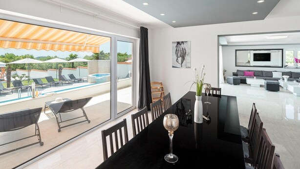 A modern living room with a large TV, comfortable seating, and a dining area with a glass table.