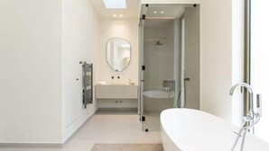 A modern bathroom with a large bathtub, a glass shower enclosure, and a vanity with a mirror.