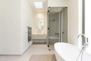 Un baño moderno con una bañera grande, una cabina de ducha de vidrio y un tocador con espejo.