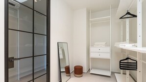 A modern bathroom with a glass door, a mirror, a white vanity, and a hanging rack.