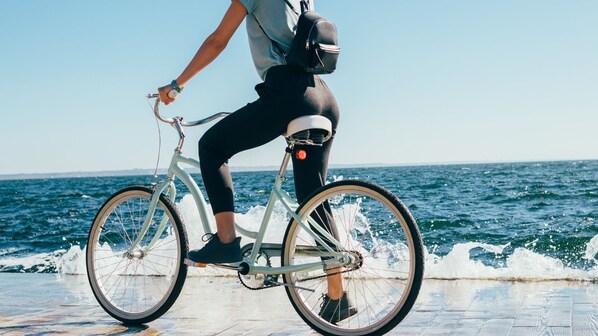 Una persona montando en bicicleta por un camino pavimentado junto al mar.