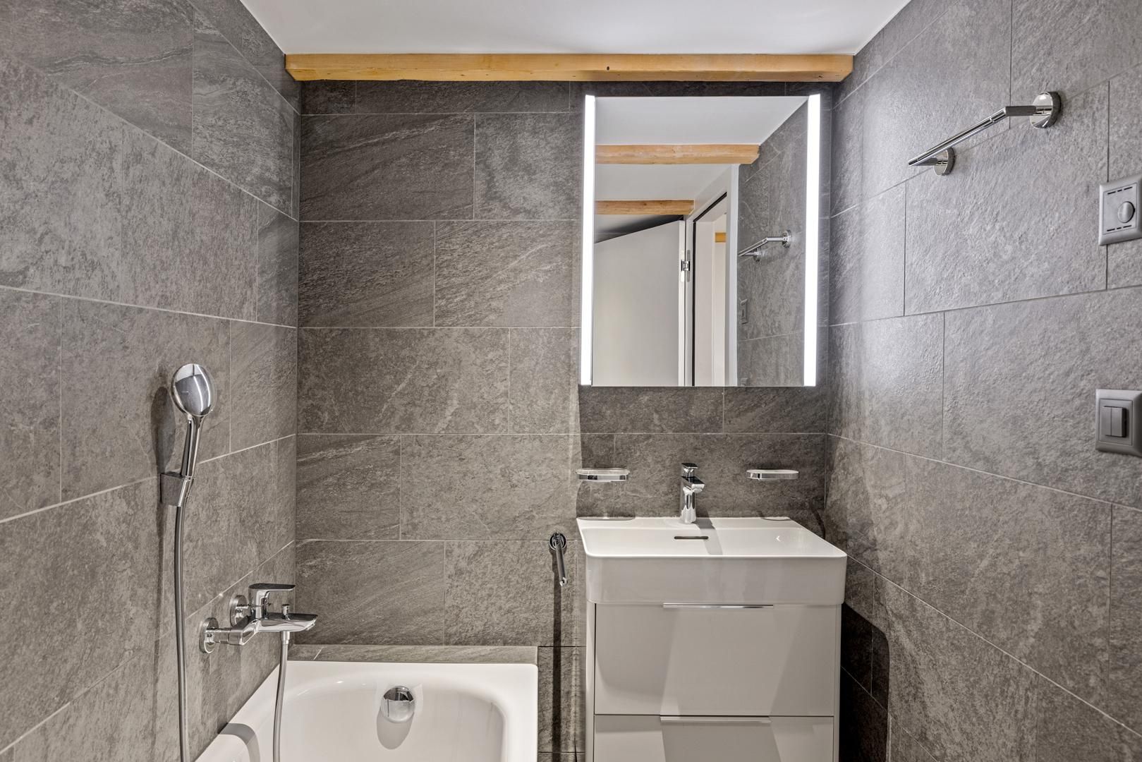 A modern bathroom with a bathtub, a sink, and a shower.