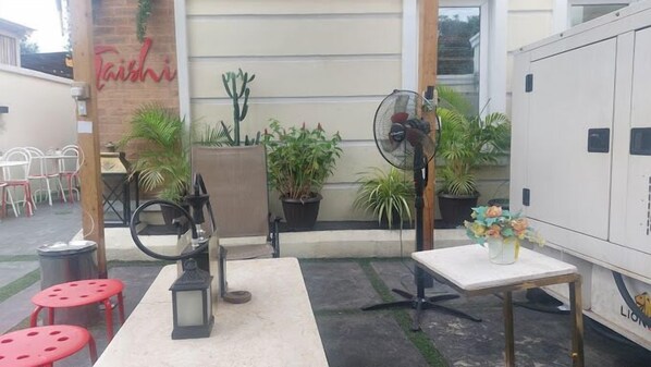 An outdoor seating area with tables, chairs, and potted plants. - Taishi Hotel (Lagos)