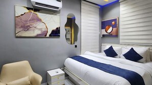Een moderne slaapkamer met een groot bed, nachtkastjes, een stoel en kunstwerken aan de muren.