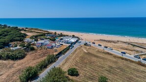 Luftaufnahme einer Küstenregion mit Strand, einer Straße und mehreren Gebäuden.