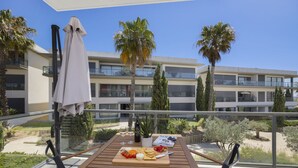Ein Balkon mit Essplatz, der auf ein modernes Gebäude und Palmen blickt.