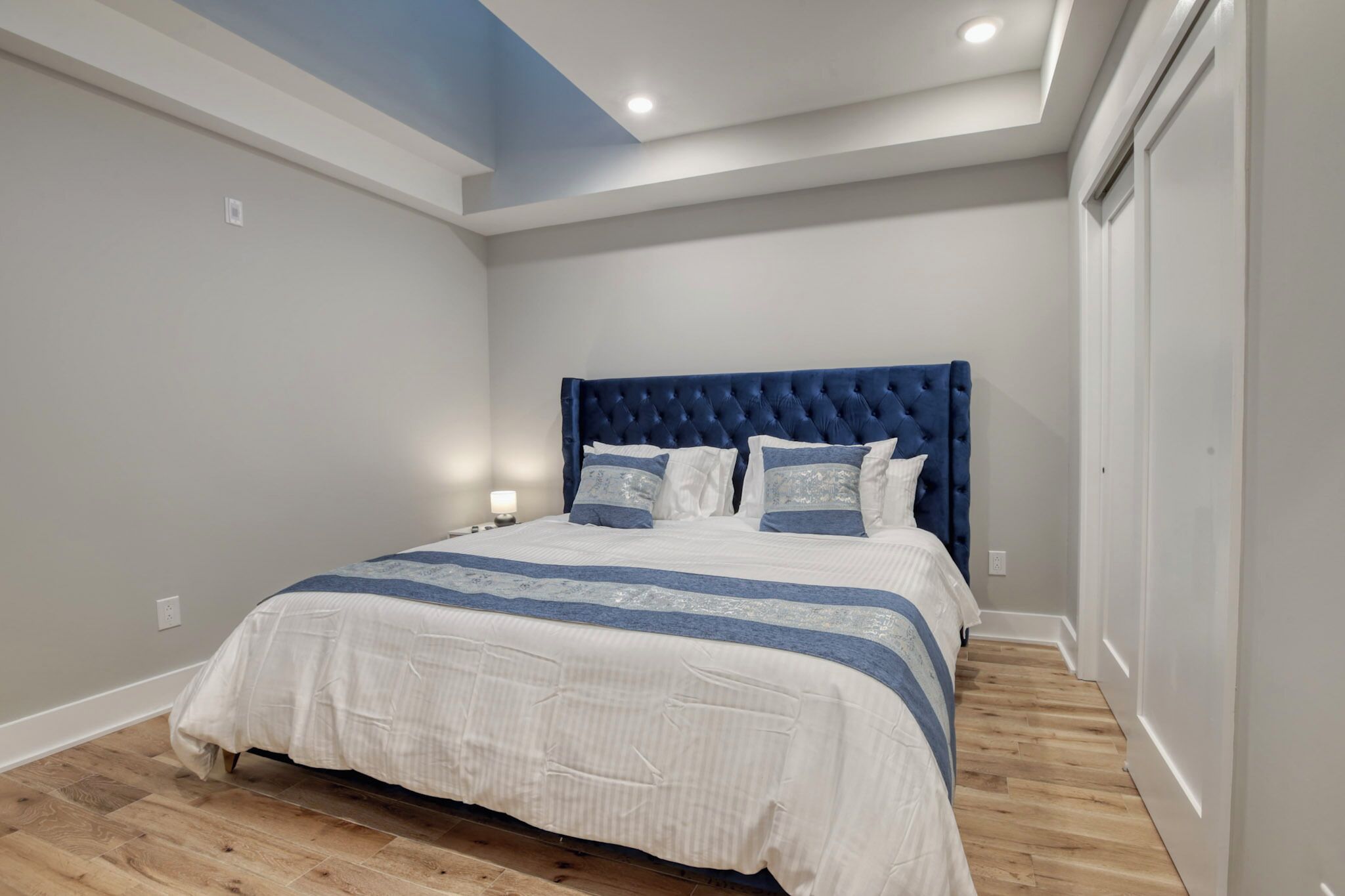 A bedroom with a large bed, a blue headboard, and a wooden floor.