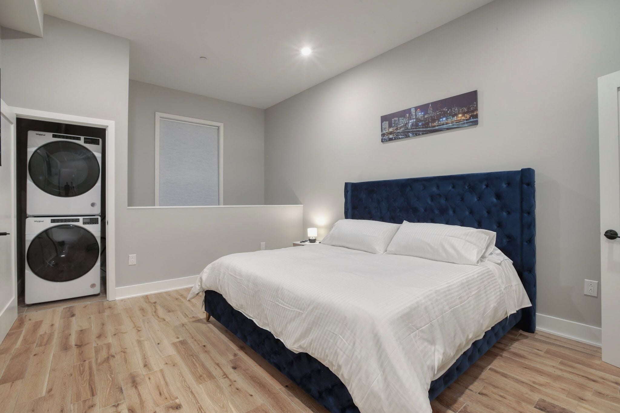 Un dormitorio con una cama grande, una lavadora y una ventana con persianas.