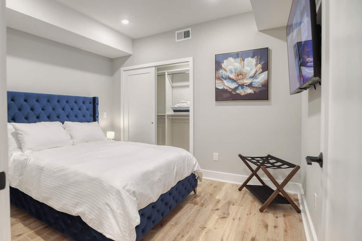 A bedroom with a bed, a wardrobe, a painting, and a TV.